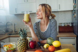 Kvinne som drikker en fargerik smoothie, fylt med ferske ingredienser, i et lyst og hyggelig miljø.