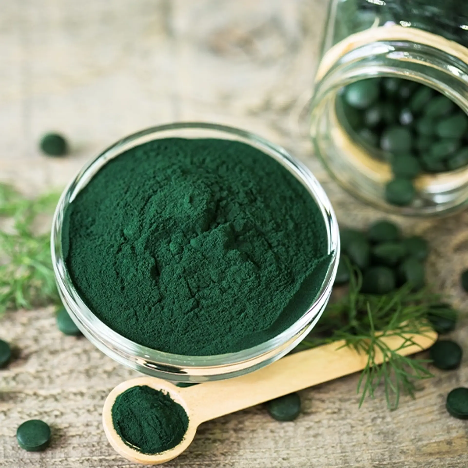 Spirulinapulver og spirulinatabletter i trebolle og skje.