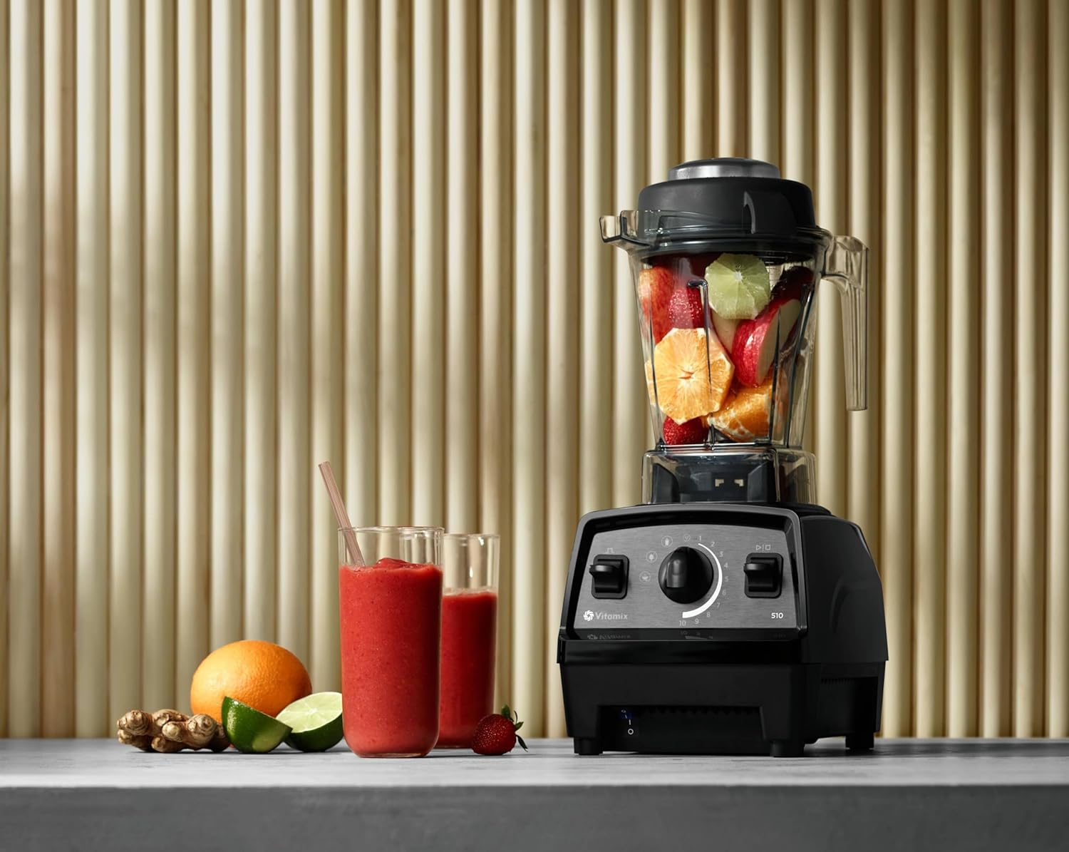 Propel 510 blender fylt med ferske ingredienser som appelsin, jordbær og lime, ved siden av ferdiglaget smoothie i glass.